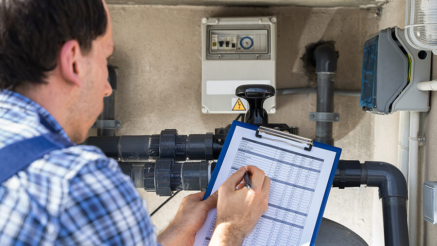 Worker Holding Clipboard Inspecting Water Pump And Pipes